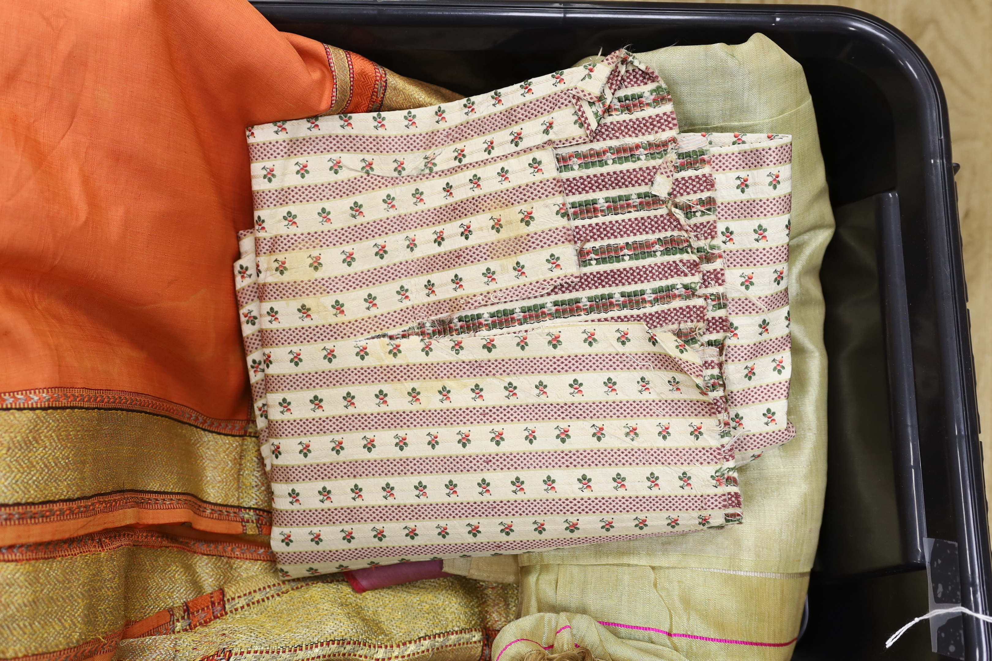 An Indian peach silk sari with woven gold borders, a fine woven gold coloured sari and part of an unmade late 18th / early 19th century ladies silk striped dress (in pieces)